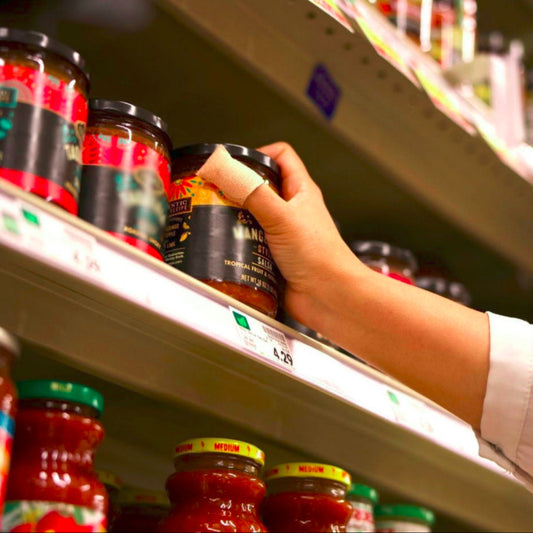 Hand selecting a jar from a shelf in a grocery store