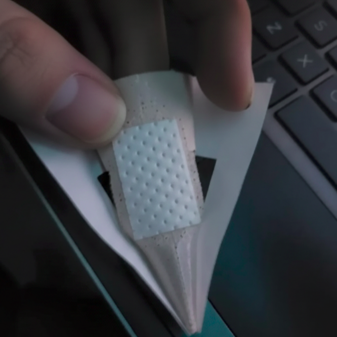 Hand holding a triangular bandage with textured surface, blurred background